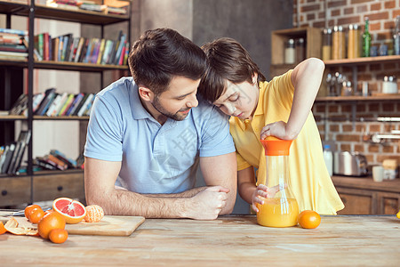 父亲和儿子在厨房桌上挤压新鲜橙汁图片