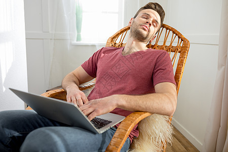 英俊的年轻人 带着笔记本电脑睡在摇椅上图片