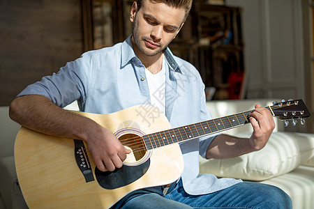 坐在沙发上弹吉他时 英俊又帅又体贴心的年轻男人图片