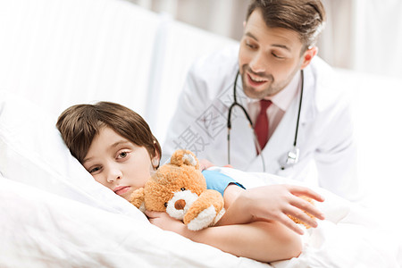 与微笑的医生躺在床后 患难儿童病人焦点卫生药品医院诊所儿科医疗孩子从业者选择性图片