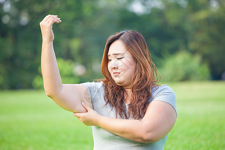 年轻女人检查她的手臂脂肪白色饮食肥胖绿色皮肤身体女性腰部腹部女孩图片