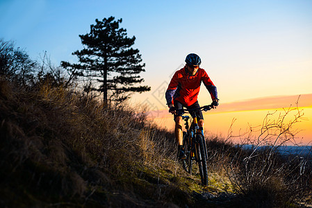 Enduro 自行车手在日落时分在岩石小径上骑山地自行车 积极的生活方式概念 文本的空间图片