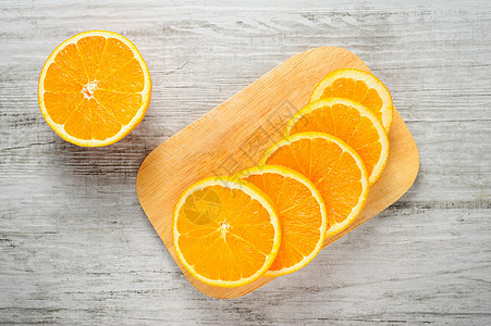 白木背景上的新鲜橙子切片宏观砧板木板水果食物热带圆形白色图片