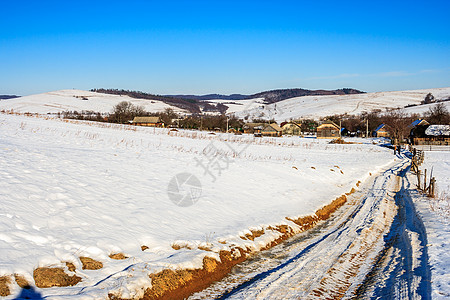 冬季沿雪坡通往老村庄的公路图片