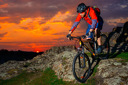 赛车手在美丽的日落山边骑着 极具活力的运动和冒险概念 的自行车下春落雪山成人山地车岩石男人乐趣竞赛下坡头盔天空速度图片