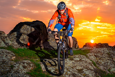 赛车手在美丽的日落山边骑着 极具活力的运动和冒险概念 的自行车下春落雪山娱乐运动员头盔速度男人成人天空岩石山地车下坡图片