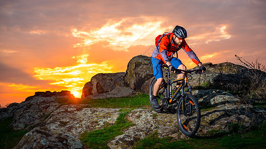 赛车手在美丽的日落山边骑着 极具活力的运动和冒险概念 的自行车下春落雪山运动员岩石山地车骑士男人头盔乐趣娱乐踪迹行动图片