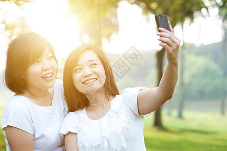女人自拍喜悦快乐女性闺蜜太阳相机耀斑假期手机照片背景图片