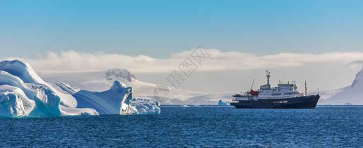 蓝游船位于有冰川背景的冰山之中图片