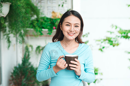 一个快乐的亚洲女人的肖像 思考和喝着咖啡或T图片