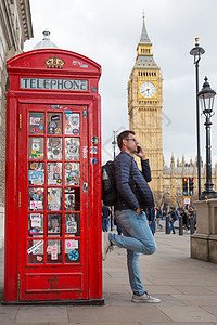 男人在用手机 红色电话箱和大班说话 伦敦 英格兰街道城市摊位讲话电话亭议会吸引力行人地标游客图片