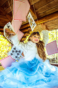 一个美丽的小女孩 玩耍和跳舞 用大牌在桌上打牌的游戏戏服女性发型化妆品仙境孩子女孩魔法艺术冒险背景图片