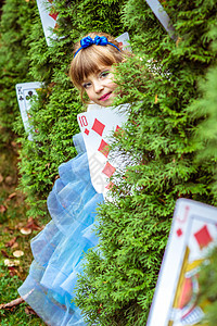 一个穿长蓝色裙子的漂亮小姑娘 看着从壁树下面看化妆品仙境魔法乐趣女孩金发女郎艺术冒险女性戏服图片