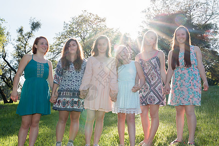 女孩与树木一起在背景中站在一起阳光女孩们姐妹太阳场地女性晴天姐姐青年天空图片