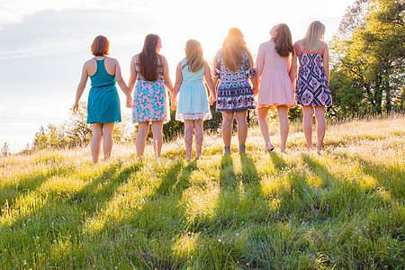 女孩在光明日落面前共同站在一起女性环境青年树木太阳晴天姐姐场地女孩们连衣裙图片