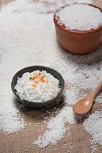 黑碗里的饭和木桌上散布的新鲜大米图片
