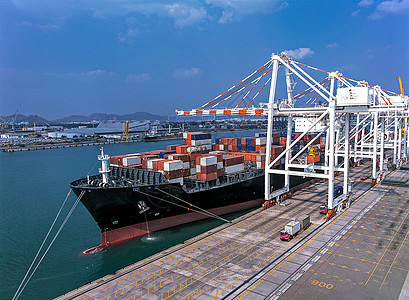港口空中观察载运货物装入船只的货船图片