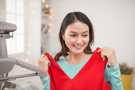 一个可爱的亚洲女孩 在家里试穿新衣服销售配件房间购物者购物零售镜子红色女士店铺图片