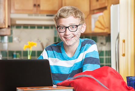 用笔记本电脑戴眼镜的可爱笑笑男孩图片