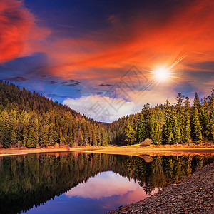 日落时山边的松林和湖射线蓝色反射天空旅游晴天山脉公园光束池塘图片