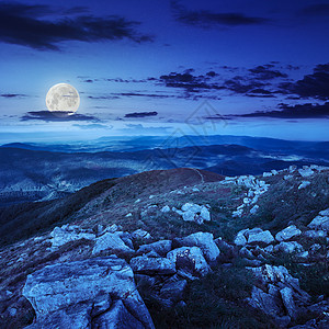 天空夜景素材在山边的石头上 在夜间天空岩石草地环境地面山坡峡谷爬坡巨石月亮背景