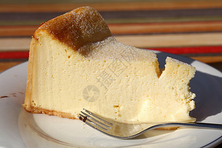 白盘上夹叉子的芝士蛋糕切片美食桌子食物盘子白色甜点桌布面包黄色棕色图片