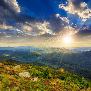 日落时在山边的石头上绿色戏剧性太阳天空旅游风景阳光山坡岩石环境图片