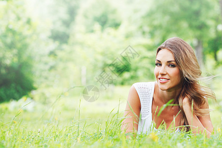 在草地上穿白衣服的年轻女子成人白色金发微笑幸福绿色裙子女孩公园女性图片