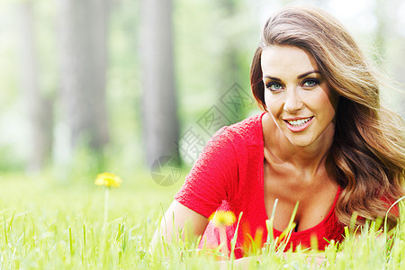 在草地上穿红裙子的女人女性女孩公园金发说谎绿色红色微笑幸福成人图片