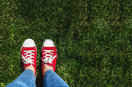 绿色草地上穿着红脚鞋的老红腿 从上面看青少年青年成人墙纸生活鞋类牛仔裤姿势幸福运动鞋图片