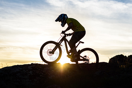 赛车手骑着山堤在日落时落的洛基山上滑雪 极具体育概念骑士冒险自行车活动运动员车轮竞赛行动山地车头盔图片