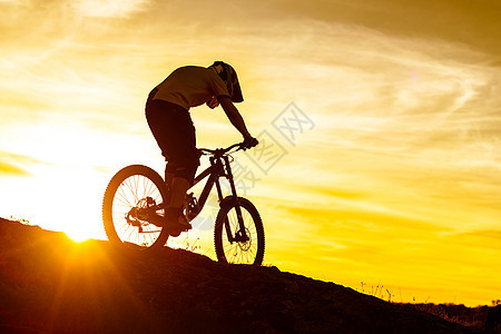 赛车手骑着山堤在日落时落的洛基山上滑雪 极具体育概念运动男性自行车岩石冒险运动员活动踪迹行动天空图片