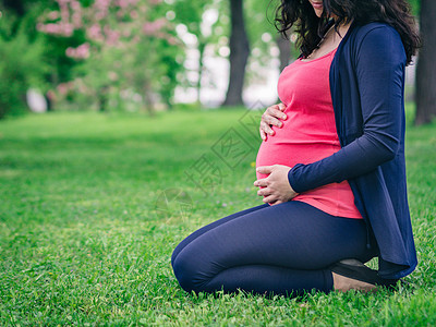 孕妇看着肚子的怀孕妇女生育力公园天空妈妈母亲黑发生活母性女士女人味图片