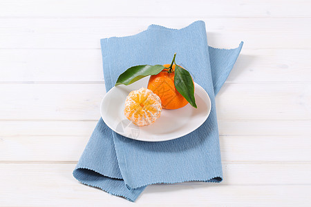 两个新鲜的橘子蓝色盘子白色餐垫折叠水果食物图片
