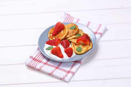 美国煎饼加酸奶和草莓油炸奶油水果蓝色抹布折叠白色小吃背景早餐图片