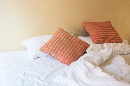 白白枕头和橙色枕头在床上 并有皱纹的乱七八糟图片