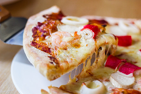 热辣海鲜披萨切片 在生锈木制标签上加融化奶酪图片