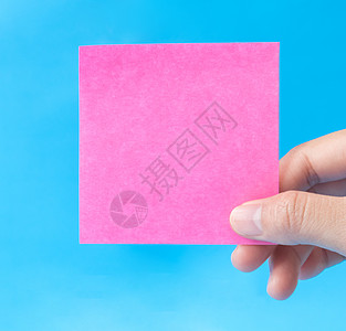妇女手持蓝色背景的粉色纸图片
