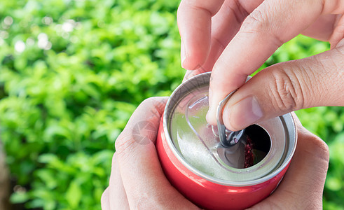 近身女人的手打开可乐 能与自然绿色黑地白色金属男性罐装自拍饮料苏打食物图片