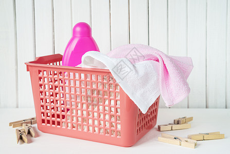 洗衣篮中的特里毛巾和洗涤剂红色洗衣店瓶子衣篮家居柔软剂粉色衣夹液体衣服图片