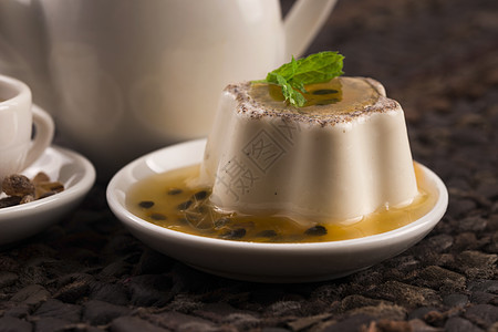 Panna cotta甜甜点与激情水果和薄荷甜点早餐酸奶烹饪奶油种子桌子木头浆果玻璃图片