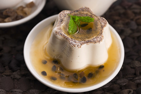 Panna cotta甜甜点与激情水果和薄荷奶油小吃种子勺子桌子牛奶木头浆果明胶香草图片