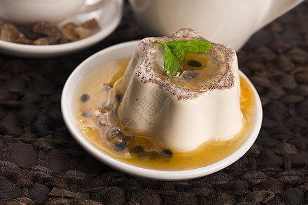 Panna cotta甜甜点与激情水果和薄荷奶油烹饪牛奶小吃玻璃焦糖食物奶制品叶子热情图片