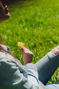 坐在草坪上闻着花香的女人白色快乐微笑草地晴天享受喜悦女性公园女孩图片