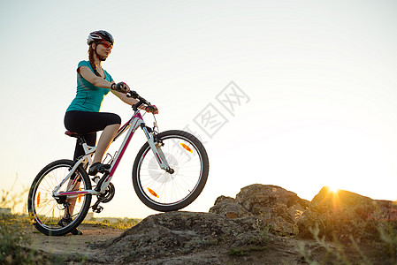 年轻女子骑着山车在美丽的日落的夏日小轨迹上 旅行 体育和冒险概念天空山地车活动运动员运动踪迹成人头盔女性自行车图片