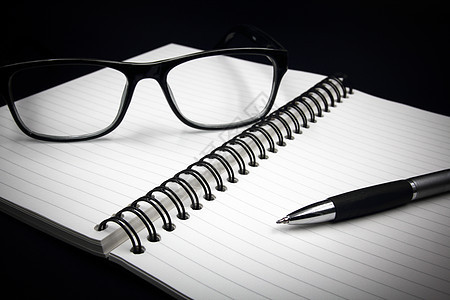 笔记本眼镜和笔 在黑色背景记事本桌子白色商业文档喷泉工作办公室日记笔记图片