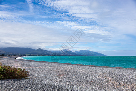 新西兰Kaikoura附近的海滩岩石蓝色支撑天空灰色白色绿色格式多云山脉图片