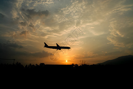 黄天日落背景的空中飞机着陆航空日出飞机场空气旅行运输天空橙子航班商业图片