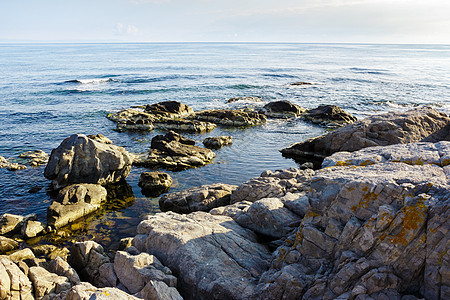 海浪在 sunris 的岩石海岸附近破碎苏醒黄色石头地平线游客旅游绿色海洋闲暇蓝色图片