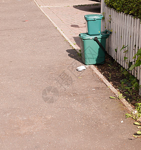 前面小路上的两个绿色垃圾食品回收箱图片